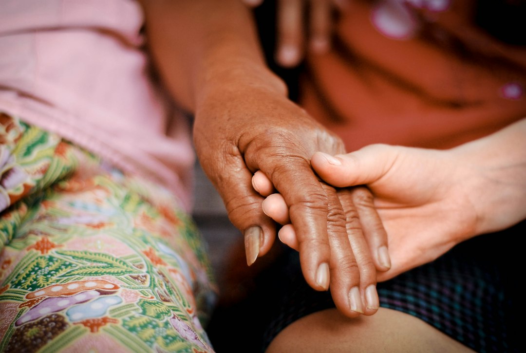 Compassionate hands supporting a patient for World Hospice and Palliative Care Day 2026