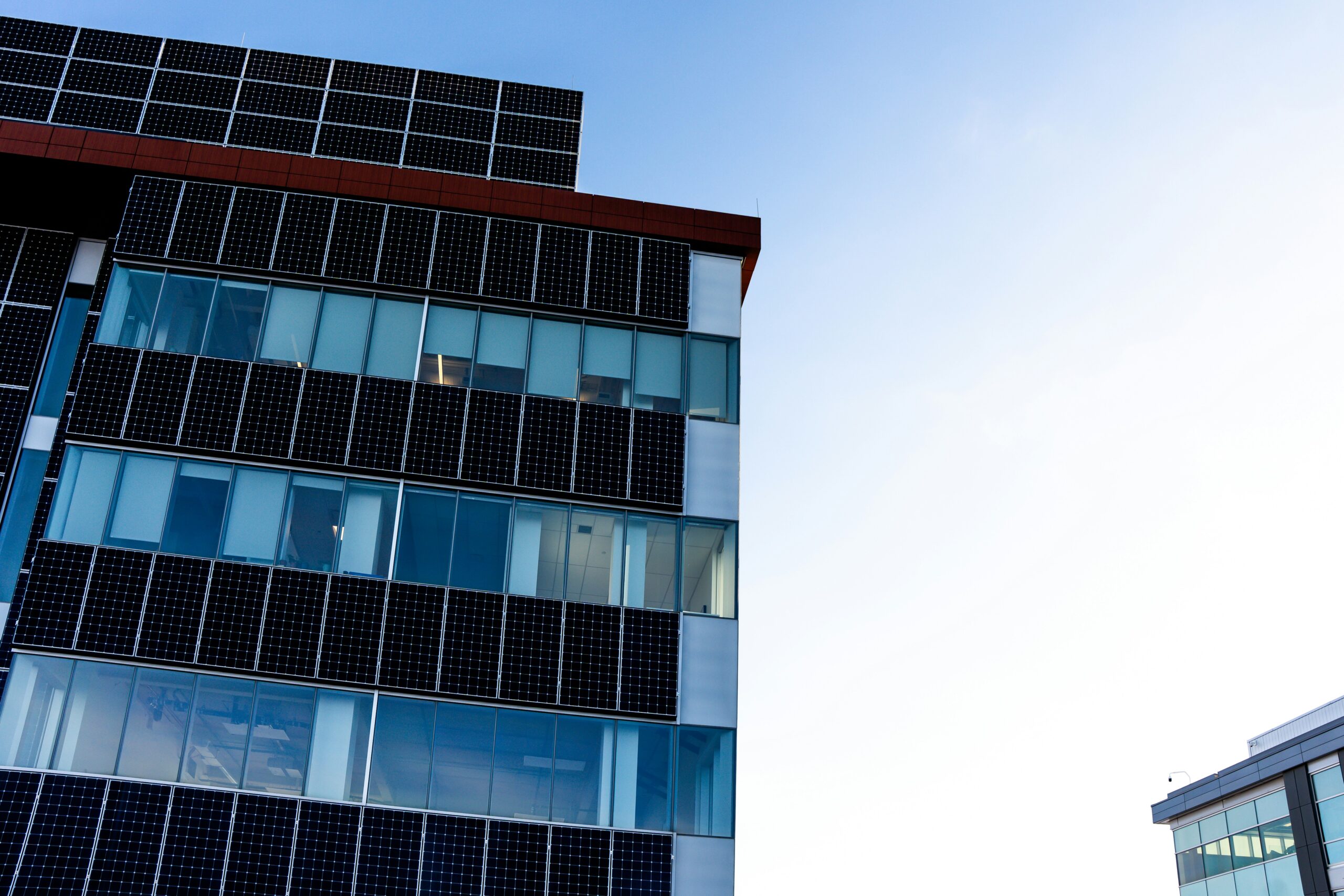 Modern commercial building facade with solar panels, illustrating energy efficiency and engineering project work