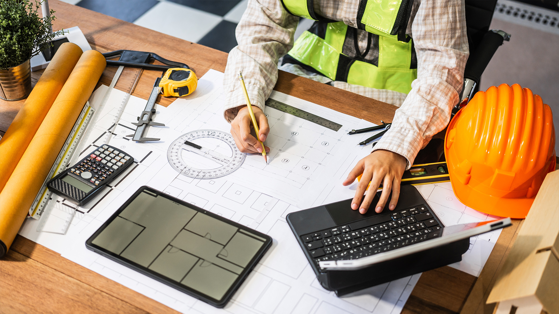 Engineering blueprints, calculator and hard hat representing Junior Engineer recruitment